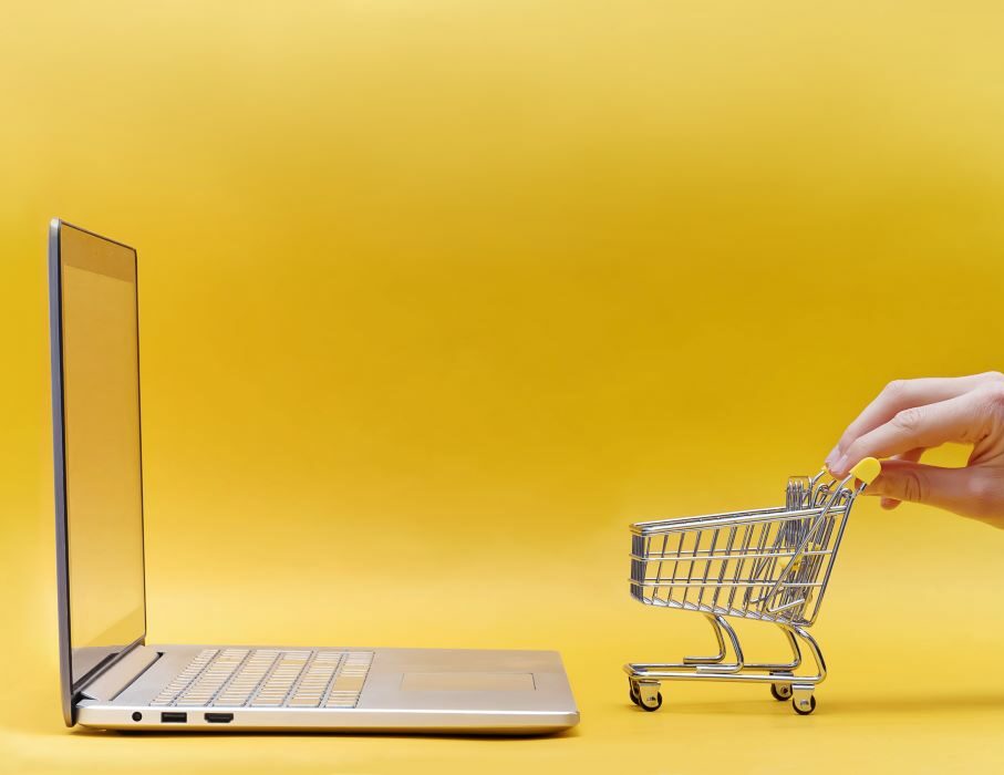 Assistance pour le e-commerce, rédaction de contrats, CGV, droit de la consommation par avocat à Marseille. Photographie montrant un ordinateur portable et un caddie miniature symbolisant les achats en ligne.